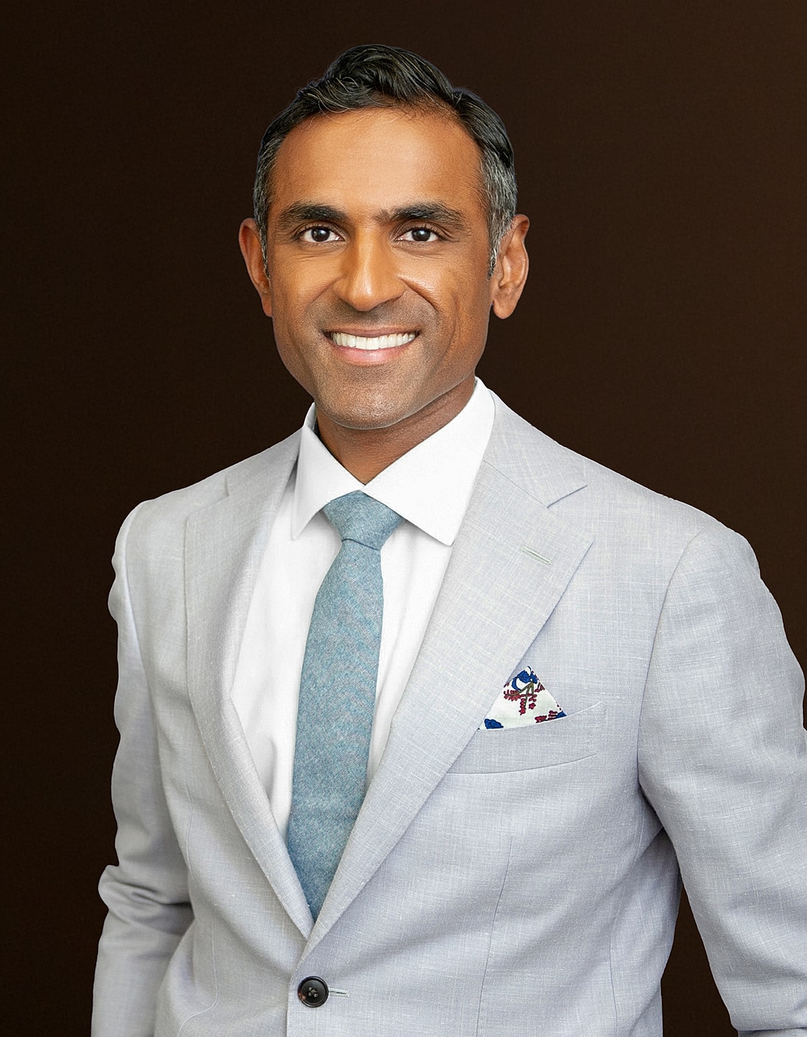 Smiling man in a light suit with tie.