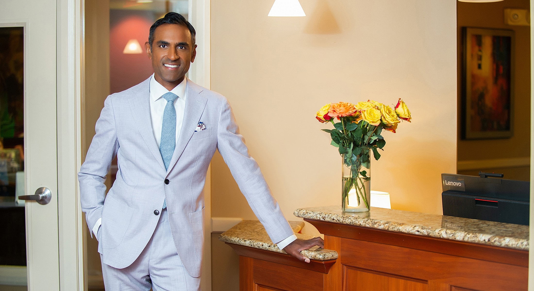 Man in suit by a reception desk with flowers.
