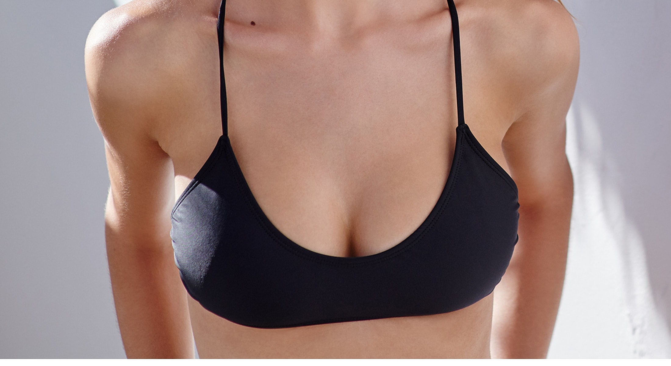 Model in neutral tank top, seated pose.