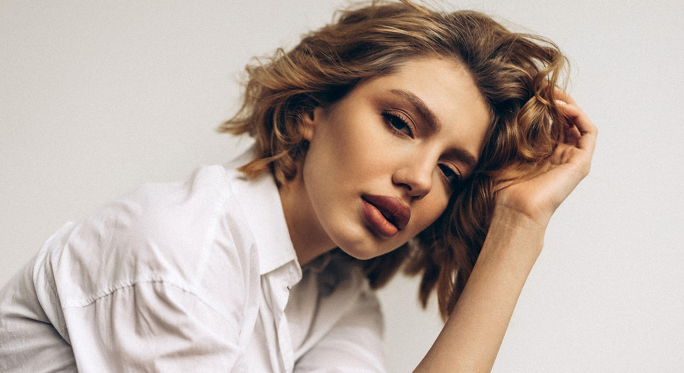 Woman with wavy hair wearing a white shirt.